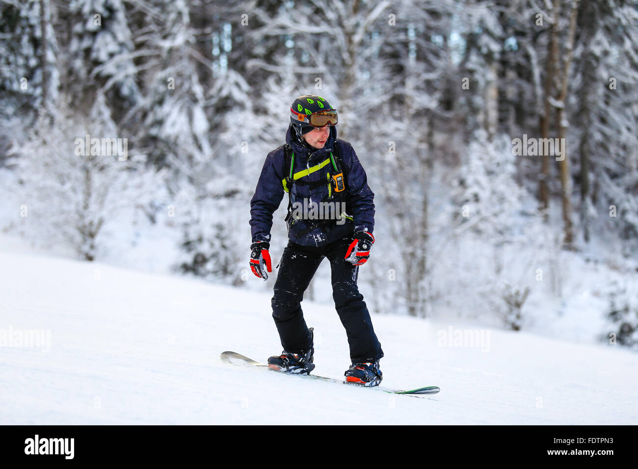 Snowboarder in black suit slides down Stock Photo