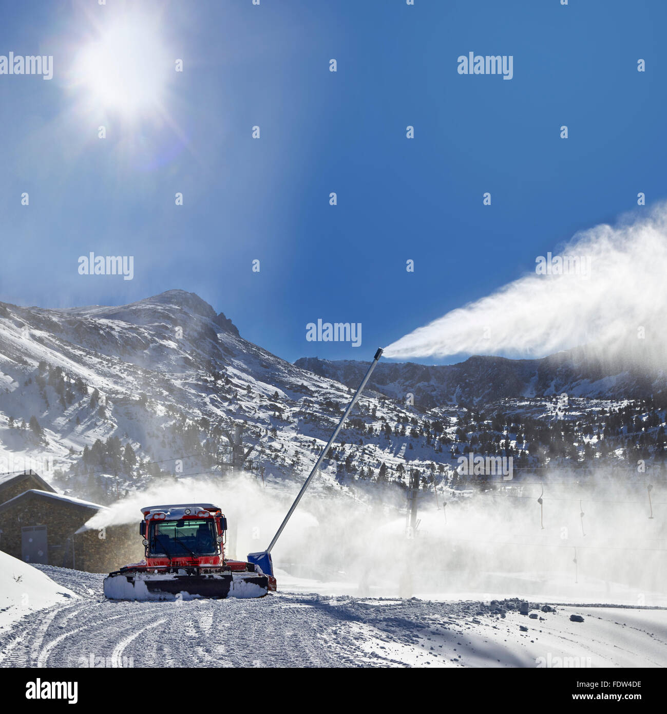 Preparation of ski resort in Pyrenees by red ratrack vehicle and snow canon Stock Photo
