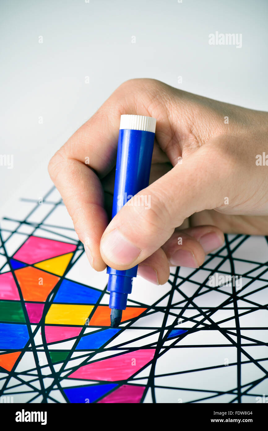 closeup of a young man coloring an abstract drawing, designed by myself, with marker pens of different colors Stock Photo