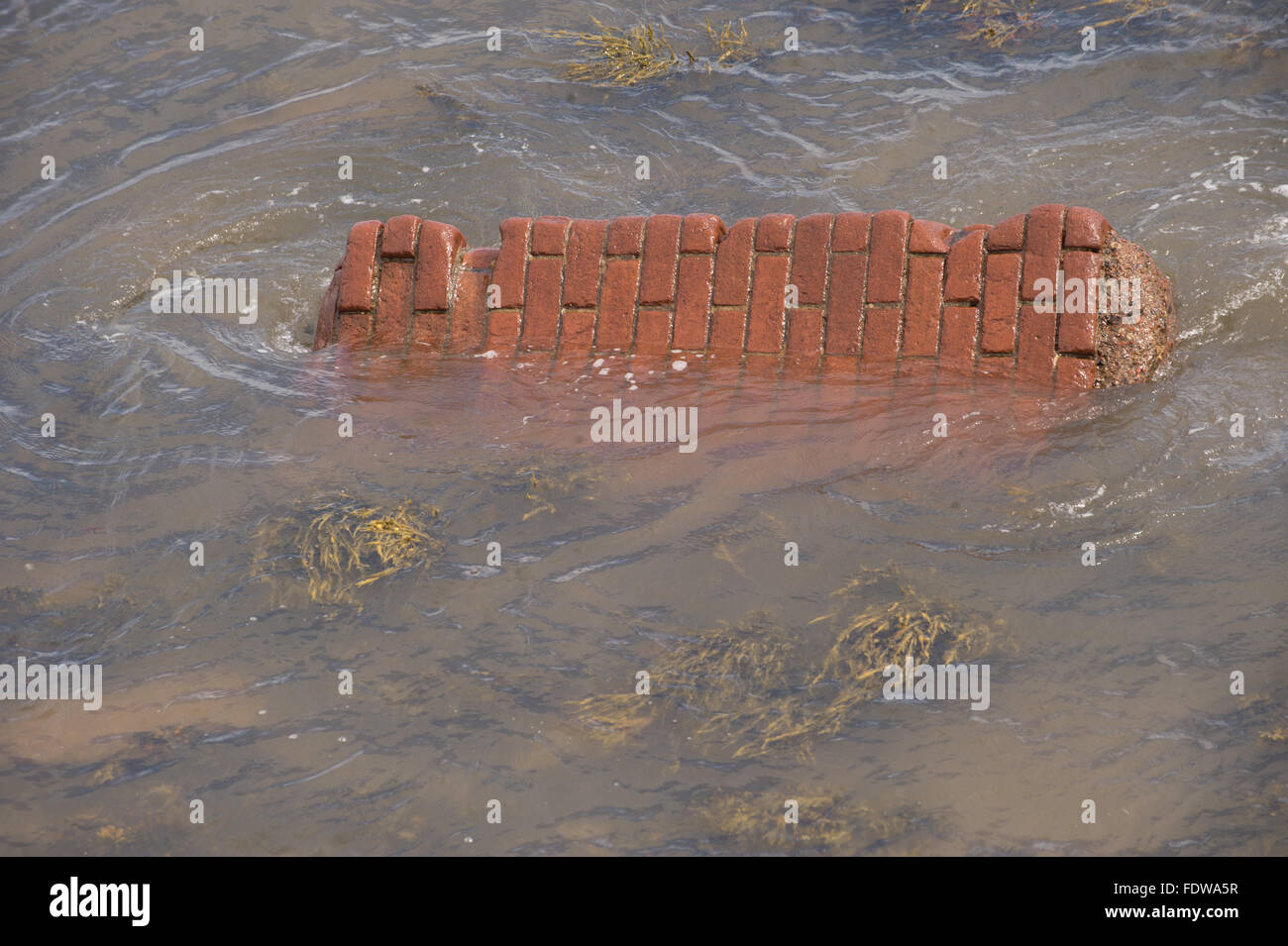 Section of collapsed brick wall under water Stock Photo