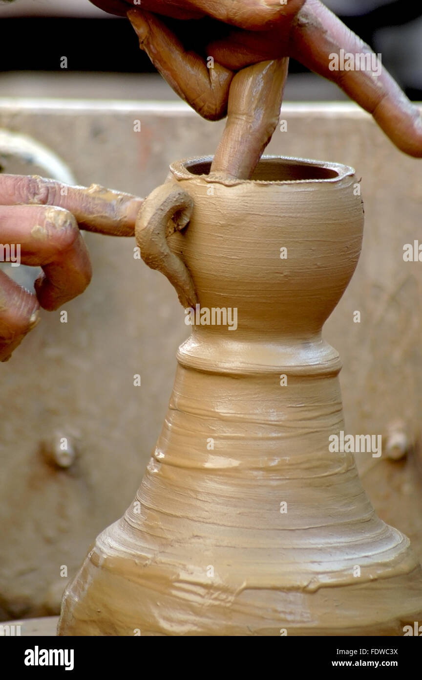 A potter making a tea cup on a clay wheel hires stock photography and