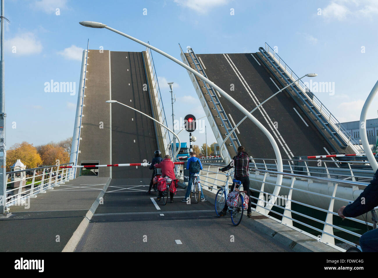 Cyclists wait as the Julianabrug Juliana Bridge opens to let a ship / barge / vessel pass underneath. Holland, The Netherlands. Stock Photo