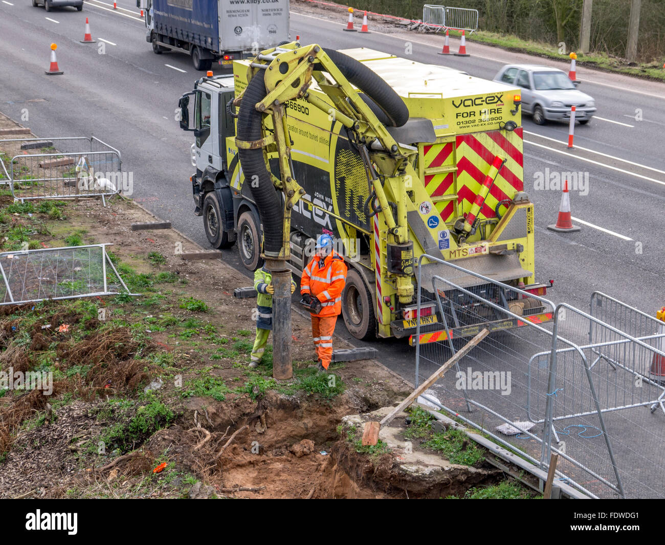 Workers on side of a coned off dual carriageway doing some vacuum excavation. Stock Photo