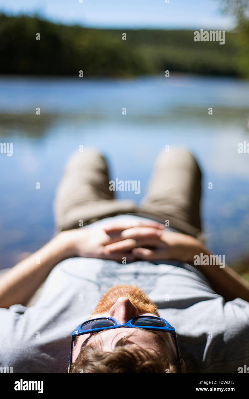 A man laying on a rock on the edge of North South lake in Upstate New York. Stock Photo