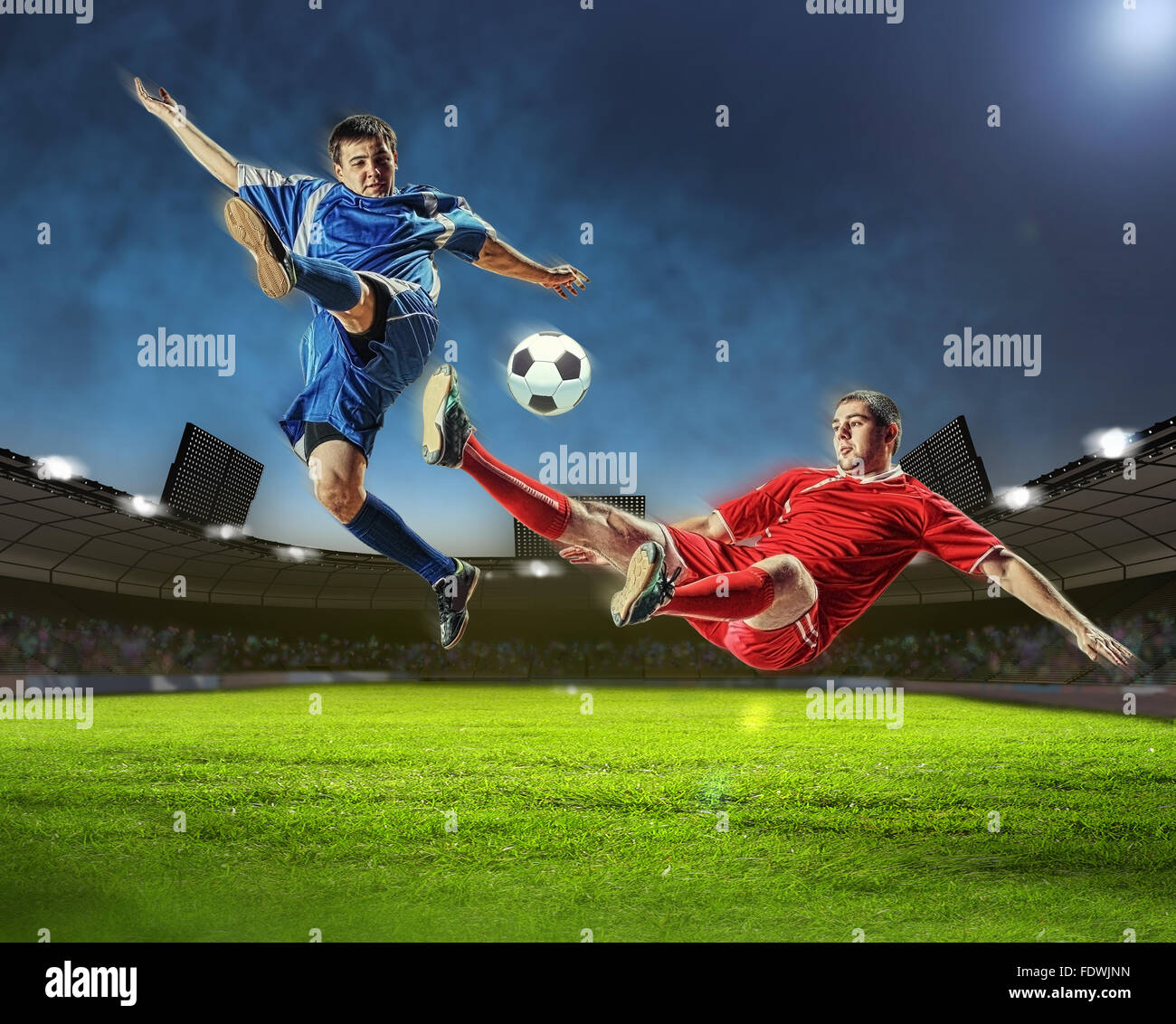 two football players in jump to strike the ball at the stadium Stock