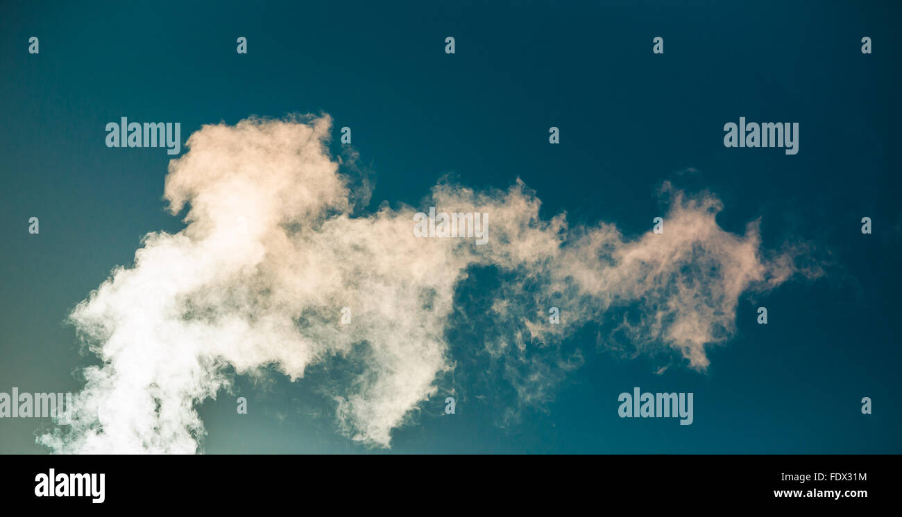 Water vapor backlit by the sun against a blue sky Stock Photo