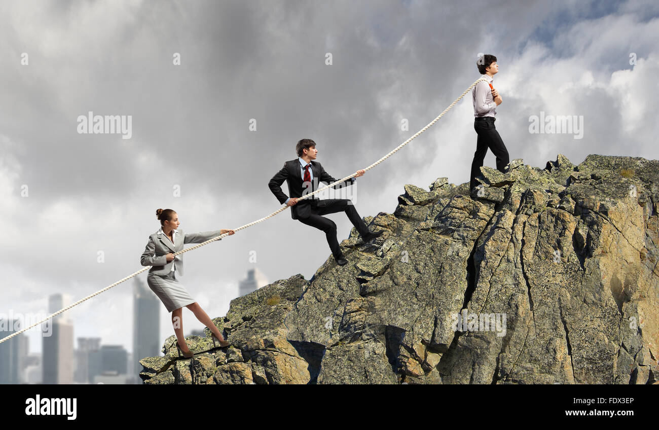 Pulling Against Rope Image of three businesspeople pulling rope against city background ...