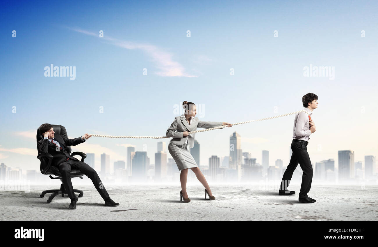 Pulling Against Rope Image of three businesspeople pulling rope against city background ...