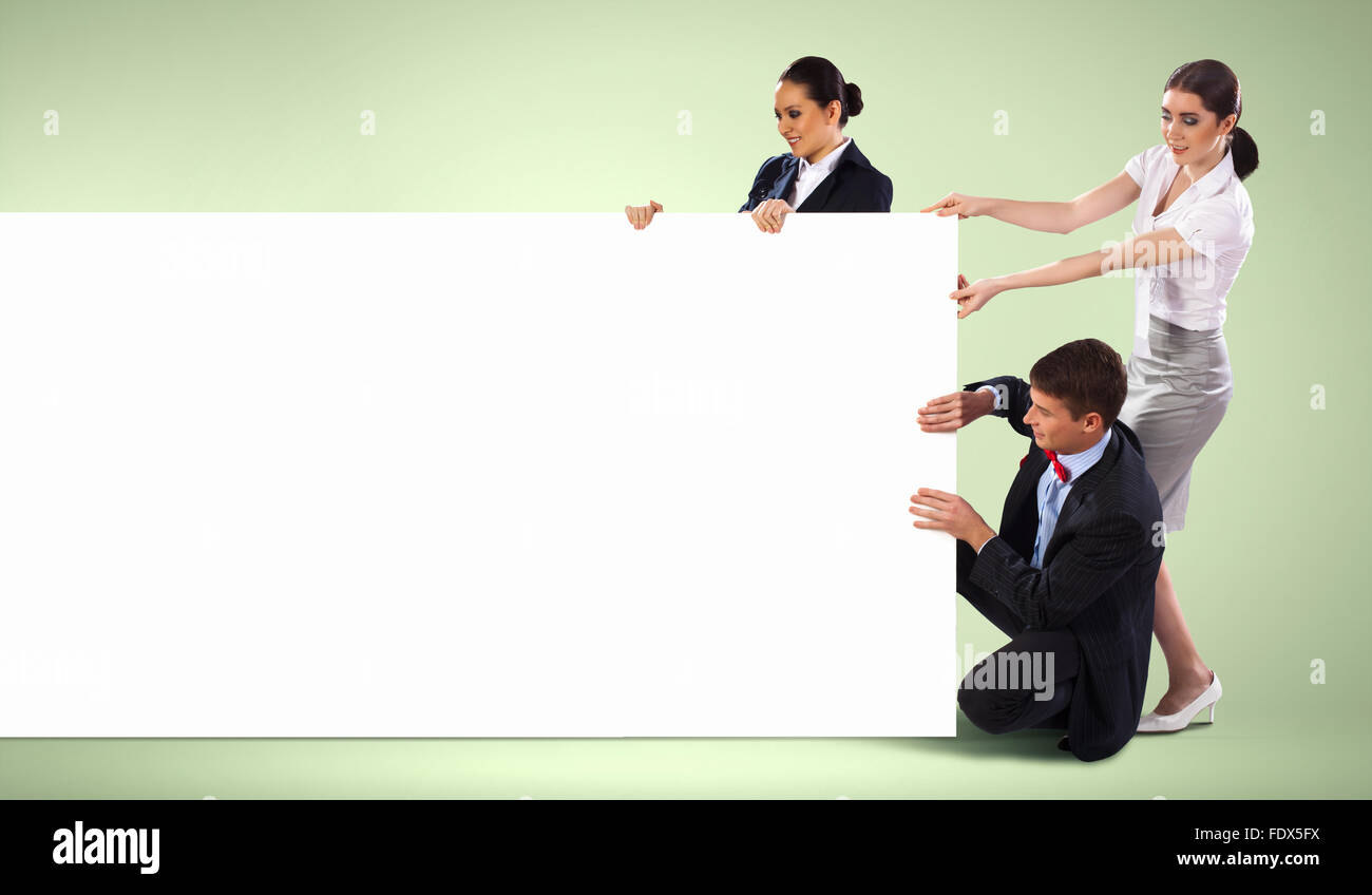 Image of three young people holding blank banner against green ...