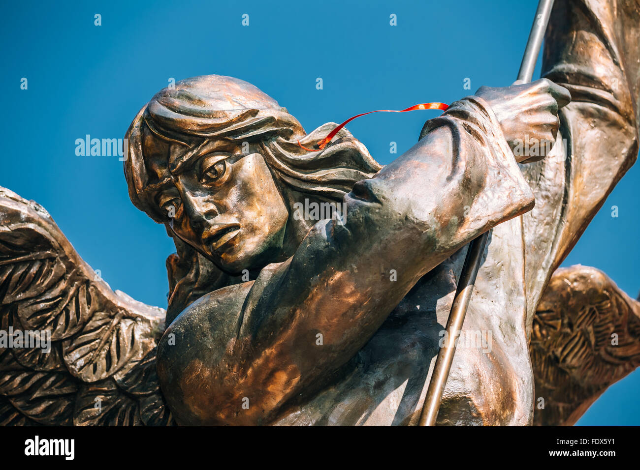 Statue Of Archangel Michael With Outstretched Wings, Thrusting Spear Into Dragon near Red Catholic Church Of St. Simon And St. H Stock Photo