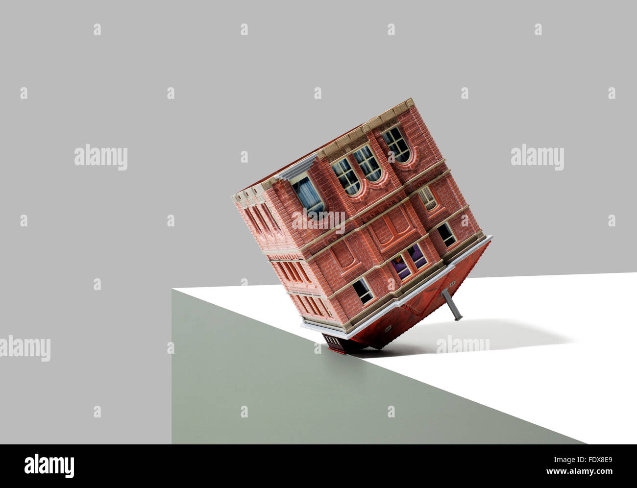 Studio shot of a model building or house upside down at the edge of cliff Stock Photo