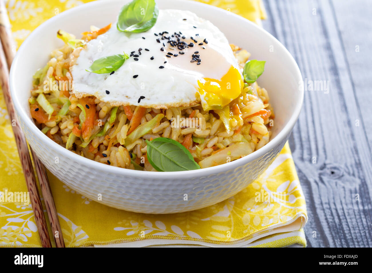 Fried rice with cabbage and carrot in a bowl with egg on top Stock
