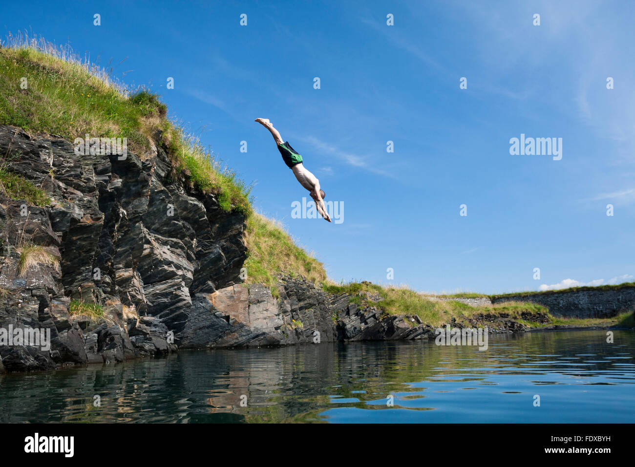 Young man diving into a quarry pool on Belnahua, Western Isles, Scotland Stock Photo