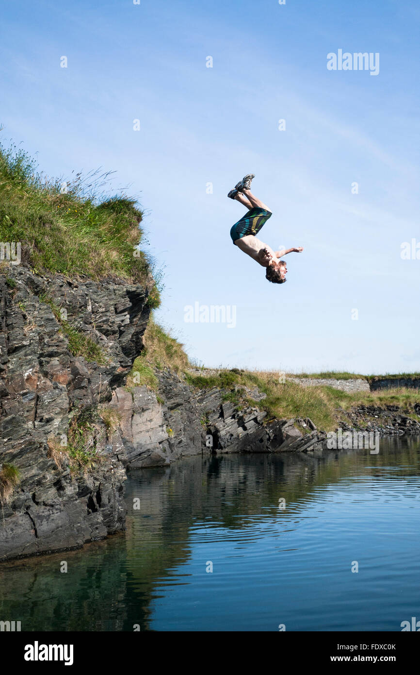 Man doing back flip into old quarry pool, Belnahua, Highland, Scotland, United Kingdom Stock Photo