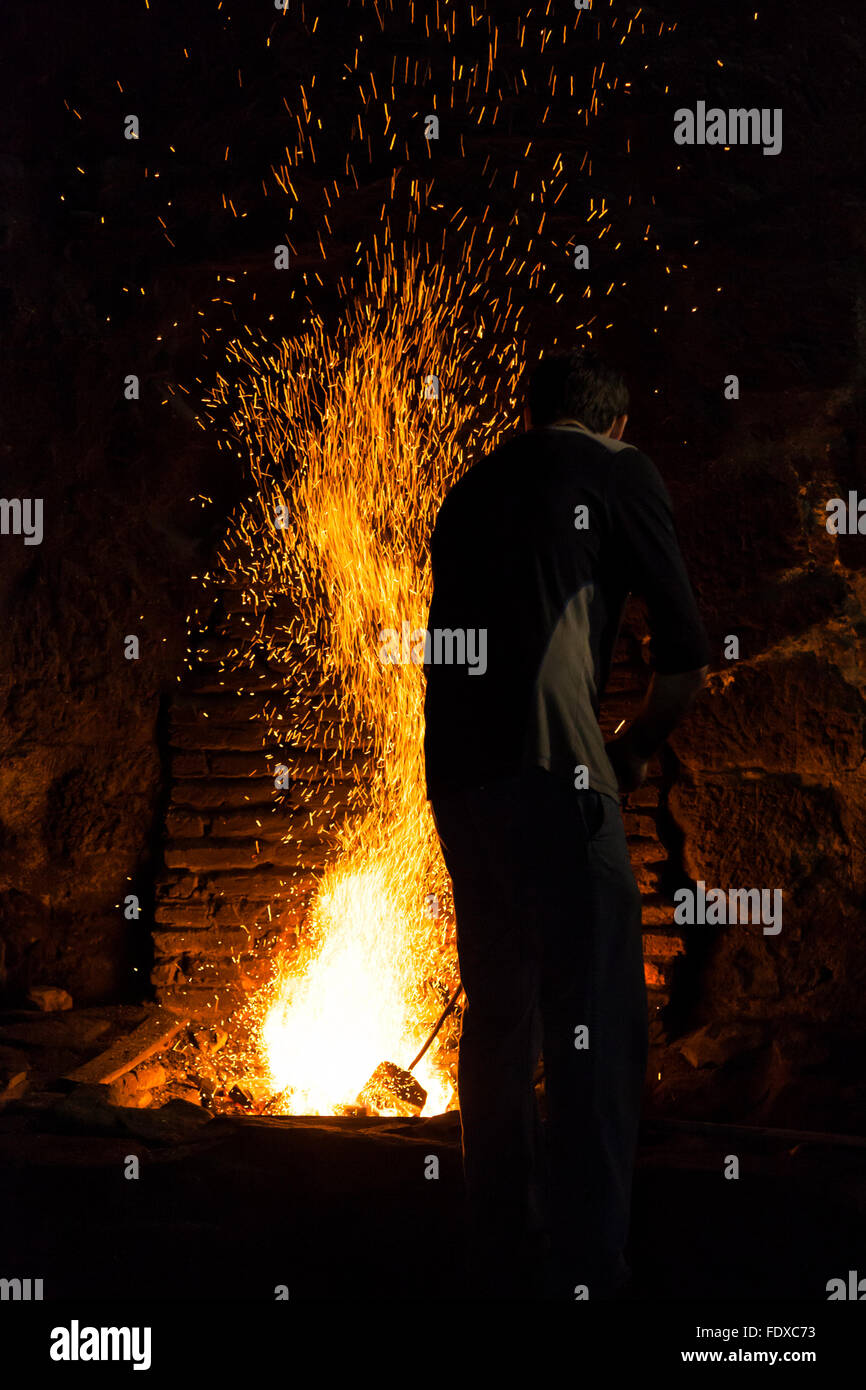 Blacksmith working in the fireplace of an old forge Stock Photo