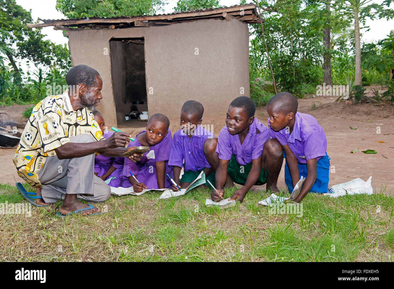 Children learning from a teacher at an outside classroom, Uganda. Stock Photo