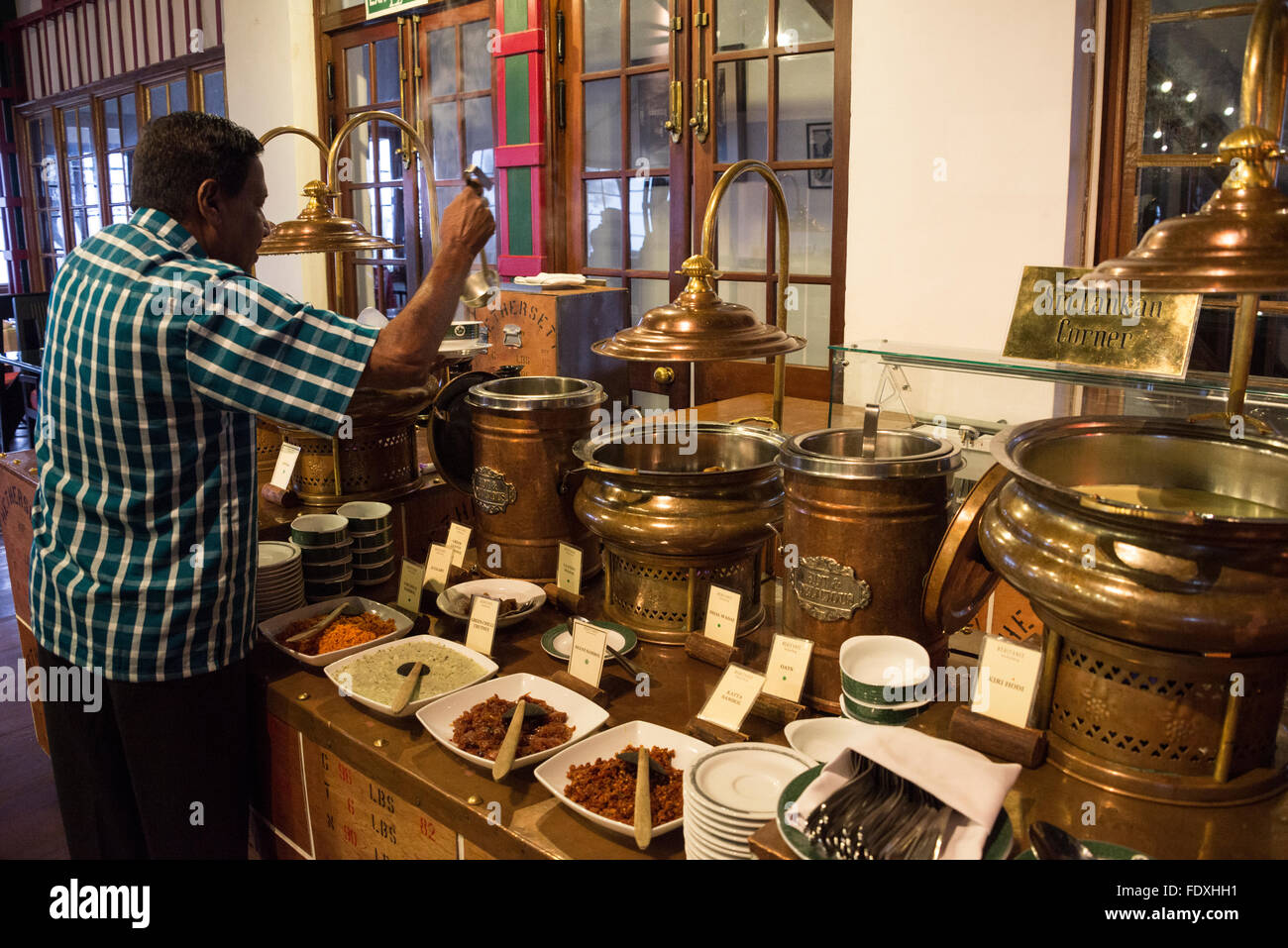 A hotel guest helps himself to one of the Sri Lankan curries in the restaurant at  the 4-star Heritance Tea Factory hotel above Stock Photo