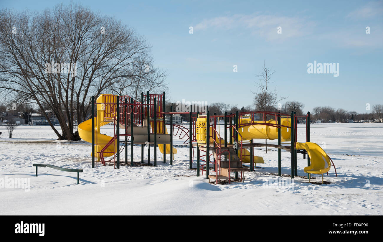 Playground equipment: slides, ladders, swings, etc.  in snow and snow drifts on a clear winter day. Stock Photo