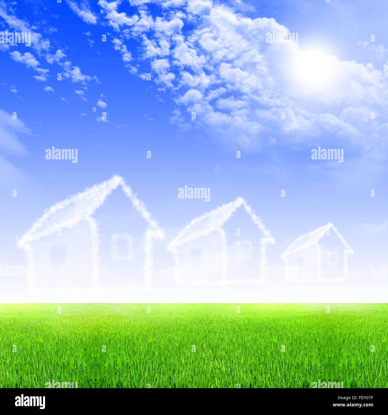 House of clouds in the blue sky against a background of green grass ...