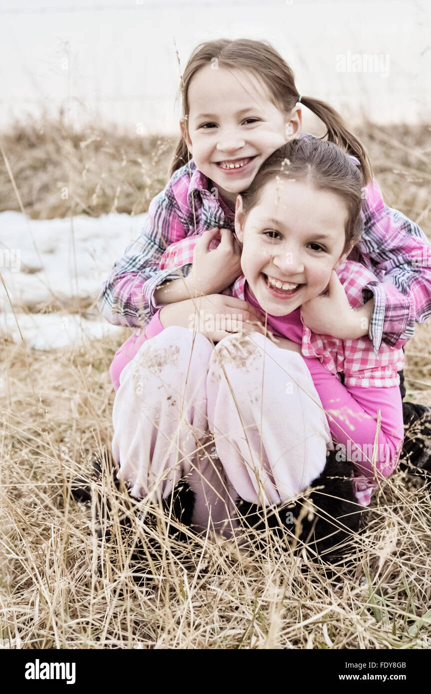 Two smiling sisters hugging in country field Stock Photo