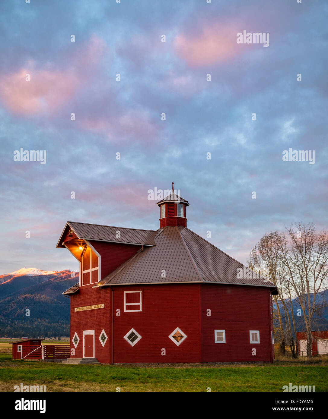 Wallowa County, OR: Octagonal barn of the Triple Creek Ranch at sunrise; Wallowa Valley with the Wallowa Mountains in the distan Stock Photo
