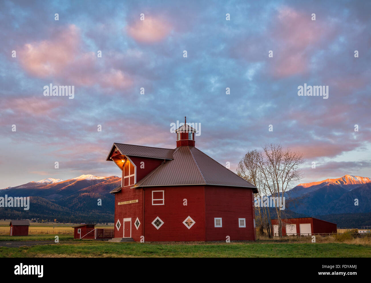 Wallowa County, OR: Octagonal barn of the Triple Creek Ranch at sunrise; Wallowa Valley with the Wallowa Mountains in the distan Stock Photo