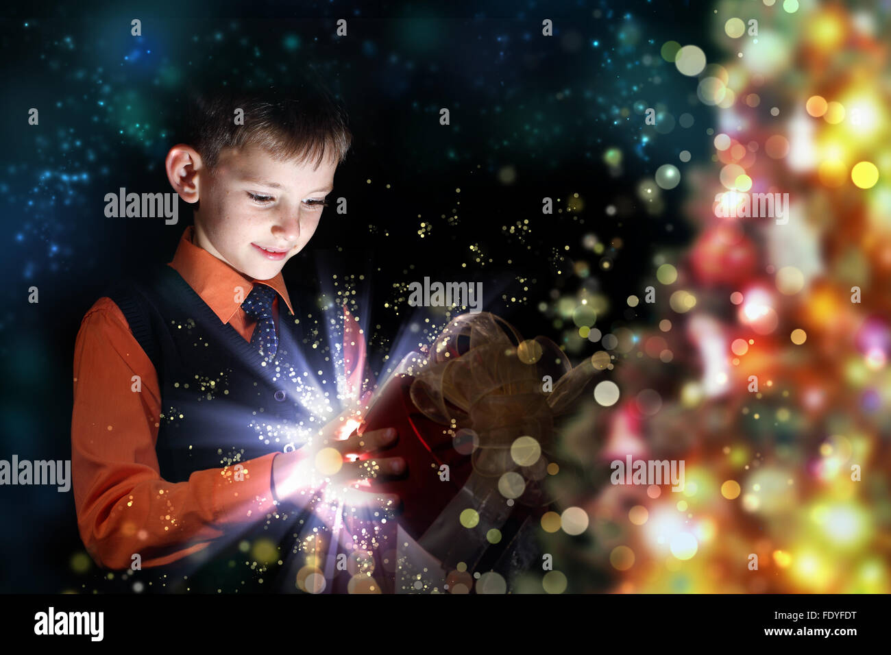 Child opening a magic gift box with lights and shining around Stock