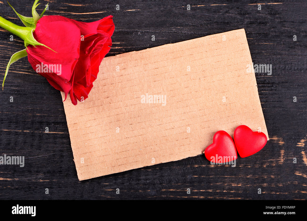 blank paper valentine card with two hearts and a red rose on wooden