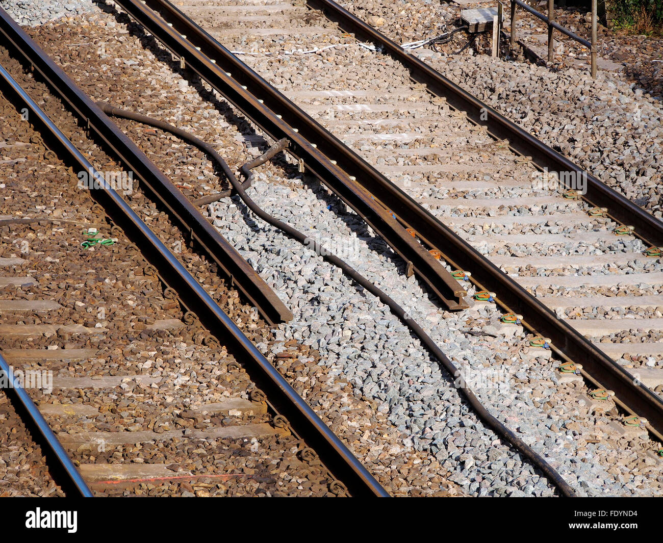 Third rail electrified railway track showing termination of electric rail at an old level crossing used for maintenance access. Stock Photo