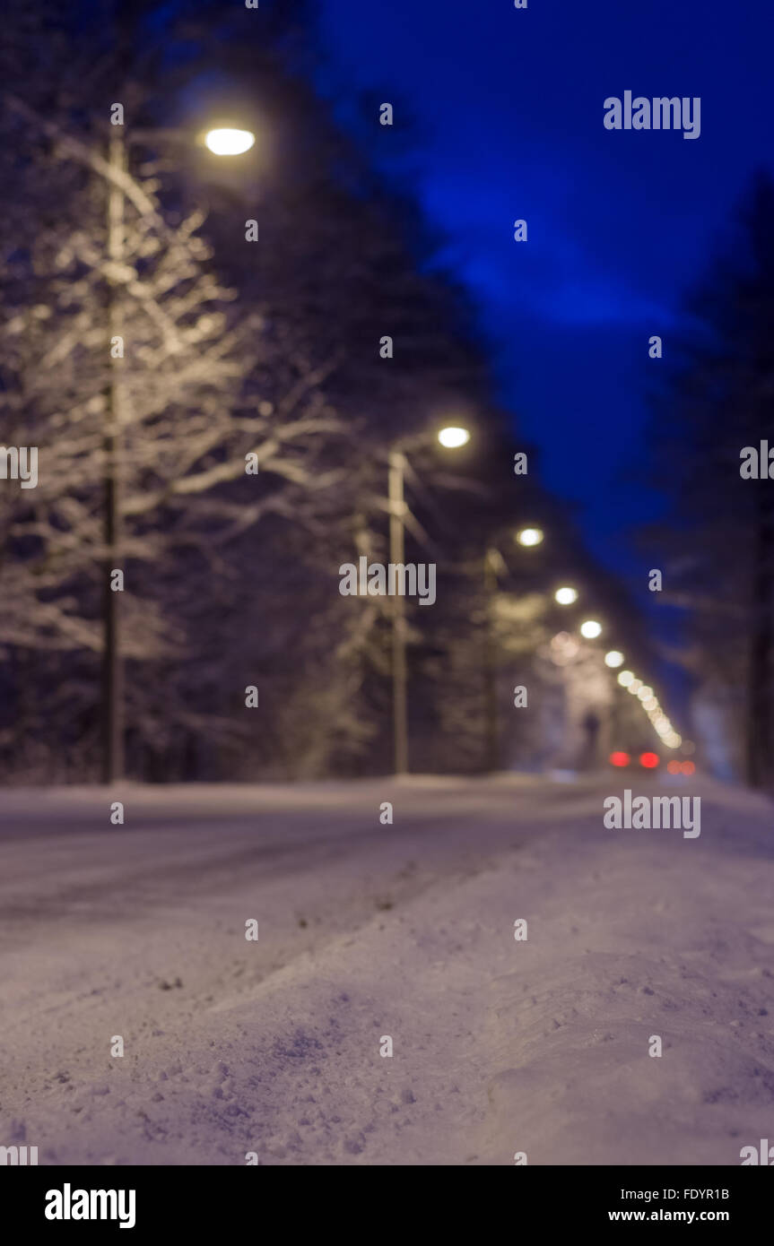 Blurred image of snowy roadside and car rear lights Stock Photo