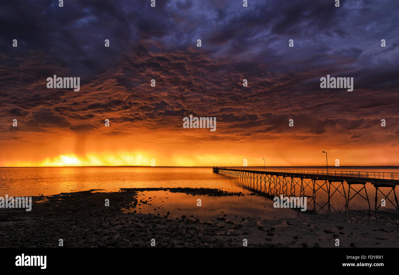 distant rainy storm over horizon in open ocean as seen from old historic wooden jetty in Ceduna, South Australia Stock Photo