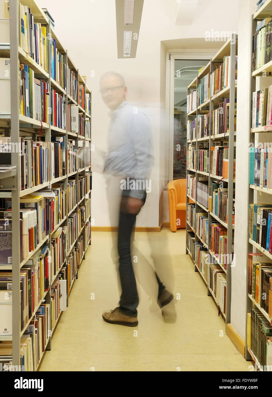 man standing and reading book in library in Pula. Stock Photo
