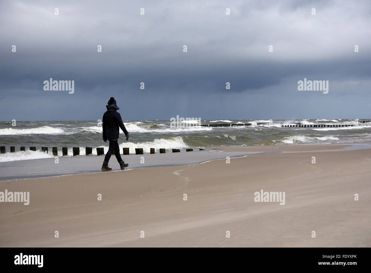 Kolberg, Poland, Woman runs in rainy weather alone along the beach Stock Photo