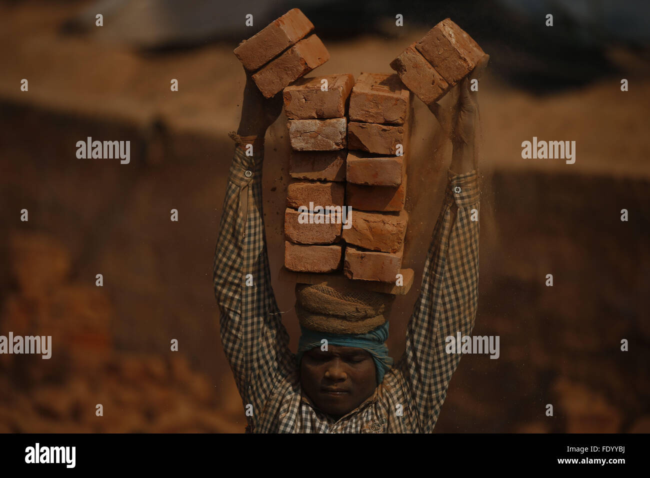 Feb. 3, 2016 - Bhaktapur, Nepal - A migrant worker stacks bricks onto his head at a Brick Kiln in Sipadol, Bhaktapur district, Nepal on Wednesday, February 3, 16. The laborers arrive during winter from India for a period of 6 months to work at Brick Kilns. Per individual a total of 16 bricks are loaded onto trucks each time to receive 1 coin that equals to Nepalese currency 0.50 paisa. In a week per person, a total of 3,500 coins are collected for Rupees 1,700  (Credit Image: © Skanda Gautam via ZUMA Wire) Stock Photo