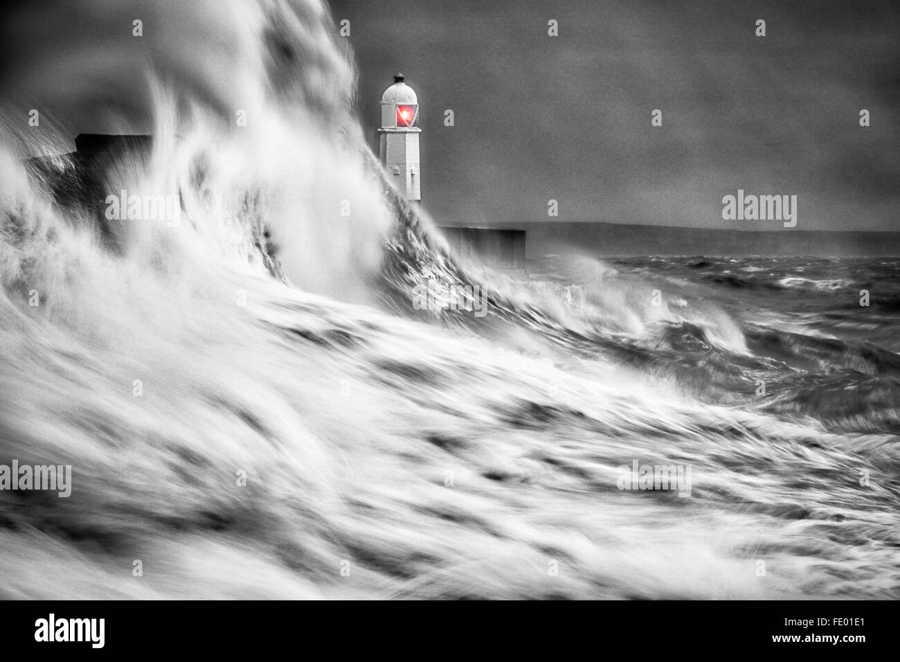 Black and white of large waves colliding into the sea wall as storm hits  Lighthouse, Porthcawl.  Bridgend, South Wales, UK Stock Photo