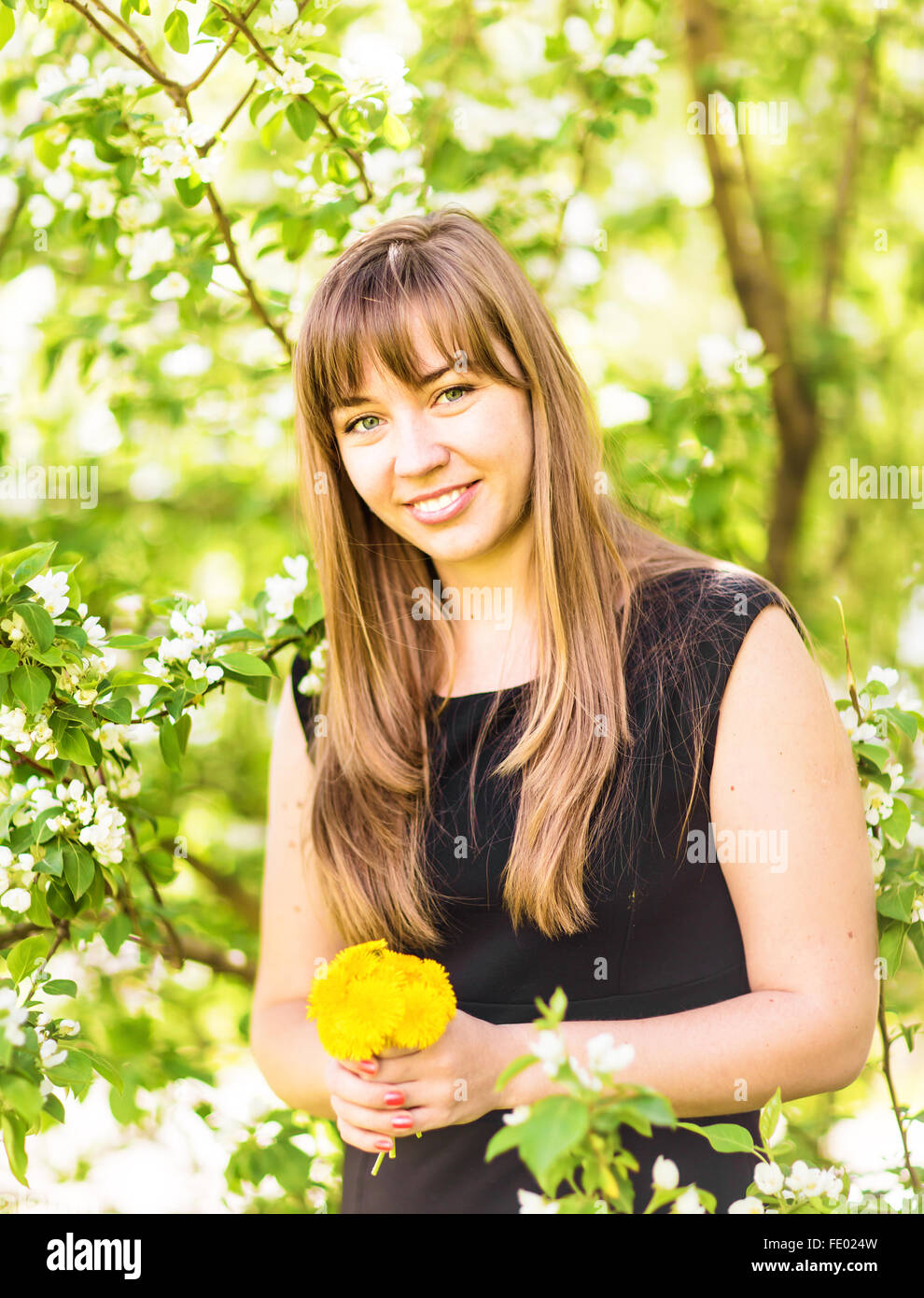 Portrait of beautiful girl with bouquet of yellow dandelions outdoor in ...