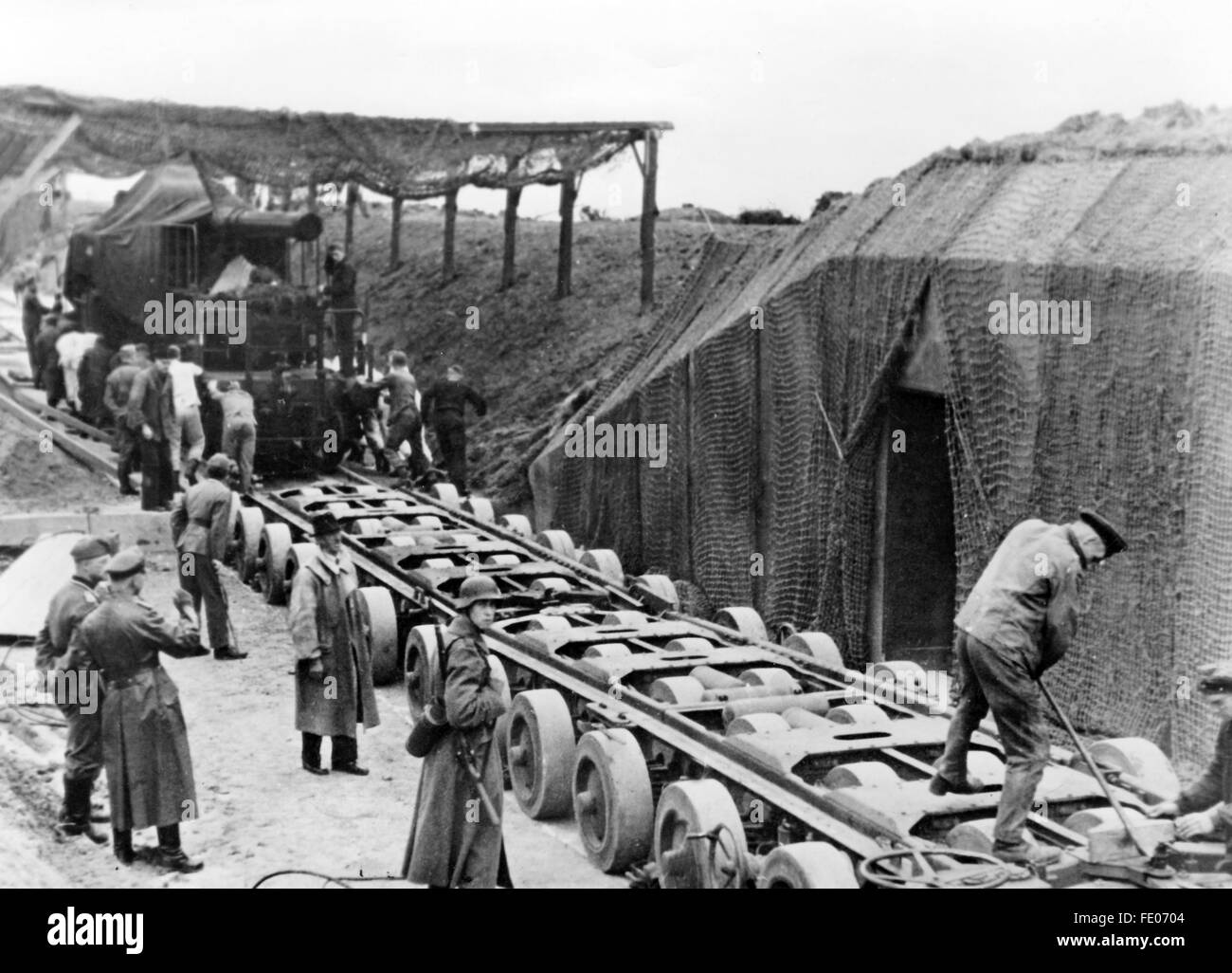 Unter dem Schutz deutscher Soldaten werden Geschütze für die Kanalbefestigungen an der Küste Frankreichs im November 1942 transportiert, Aufnahmeort unbekannt. Unter der Kennung 'Organisation Todt' wurden Befestigungs-, Verteidigungseinrichtungen und Bunker mit Abschussbasis entlang der Atlantikküste zur Abwehr gegen die Alliierten erbaut. Die nationalsozialistische Propaganda schreibt am 02.11.1942 auf der Rückseite des Bildes: 'Zwei Dutzend Räder tragen den Koloss. Ein schweres Geschütz für die Kanalbefestigungen wurde bis an seinen Standort auf einem Spezialwagen herangebracht. Diese auf zw Stock Photo