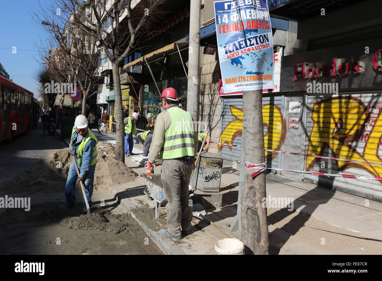 Thessaloniki, Greece. 3rd February 2016. Workers repair a pavement in front of a poster announcing a general strike and a rally. Greek public and private sector unions called for a nationwide general on Thursday to protest againts government's planned pension reforms that are part of the country's 3rd international bailout. Public transport is excepted to be severely disrupted, and taxi drivers are expected to join the action. Credit:  Orhan Tsolak/Alamy Live News Stock Photo