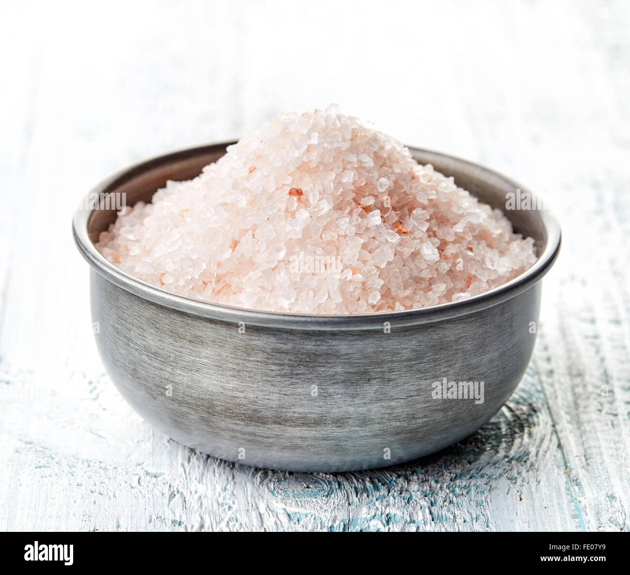 Himalayan salt in meatalic bowl on white wooden table Stock Photo