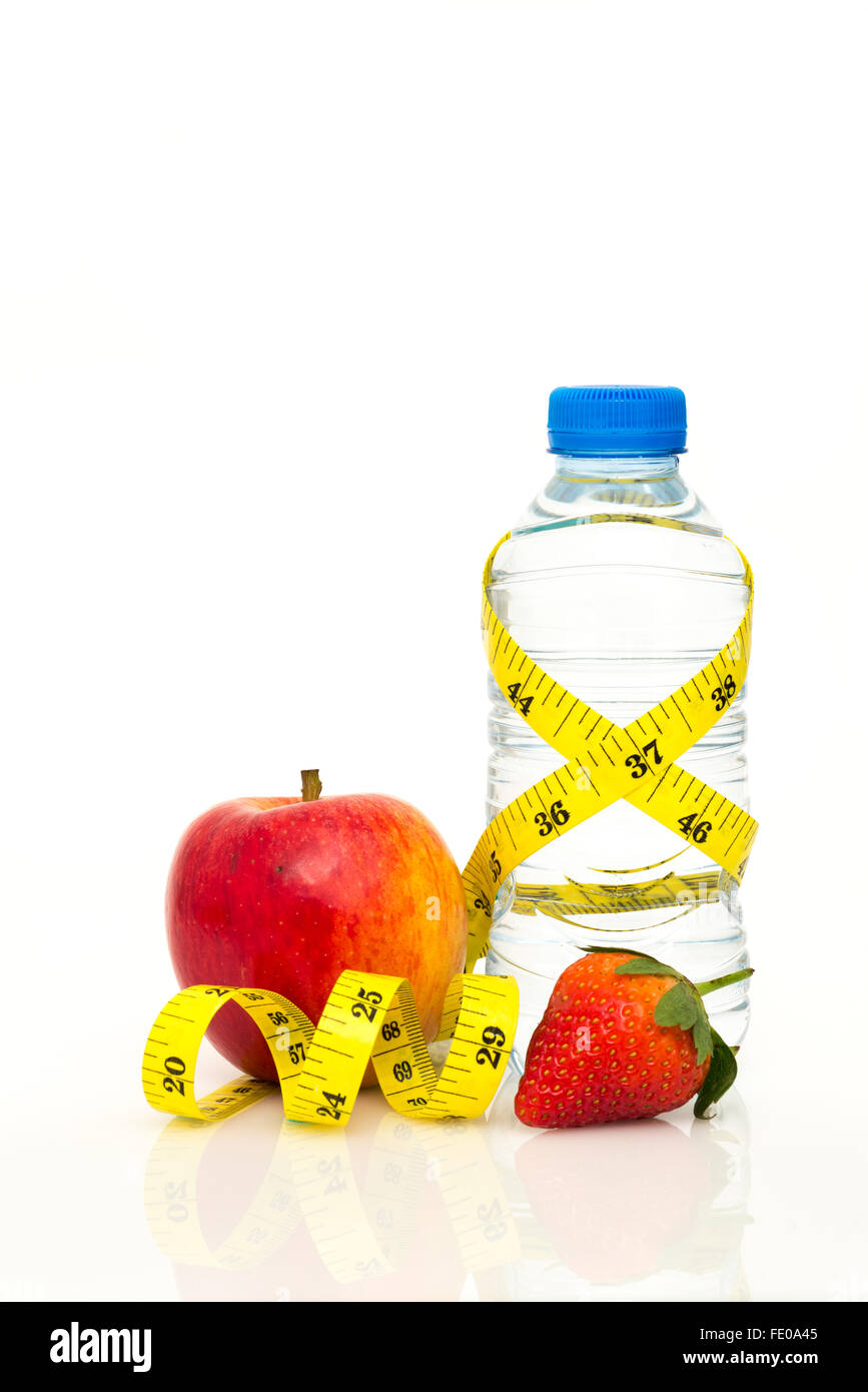 Water bottle wrapped in yellow imperial tape measure with red apple and strawberry isolated on white background with copy space Stock Photo