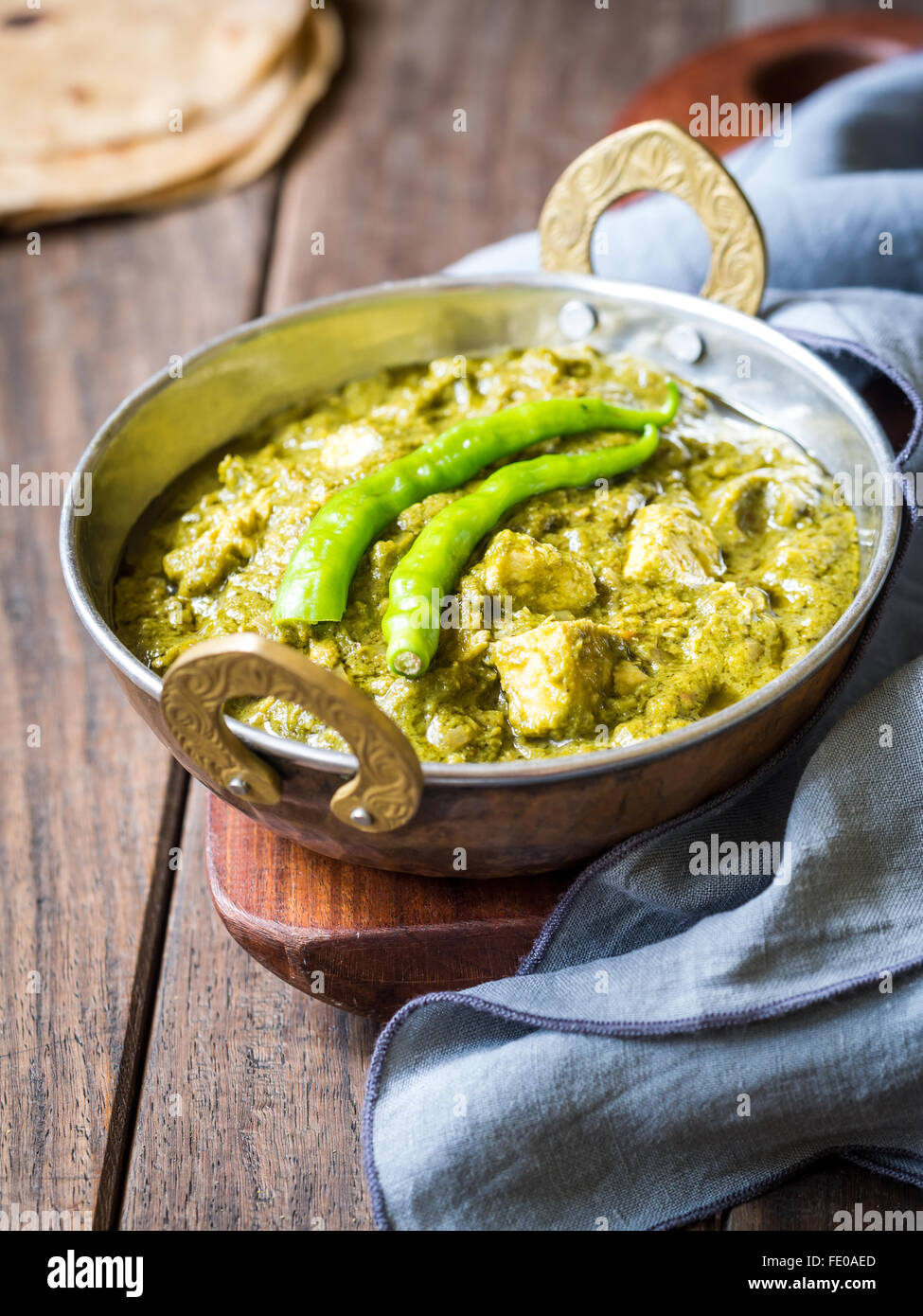Indian cuisine: palak paneer in traditional copper bowl served with tandoori roti on a dark wooden table. Stock Photo