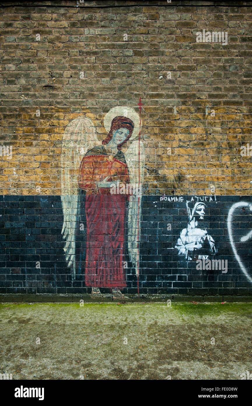 Banksy style graffiti next to religious graffiti, London Stock Photo