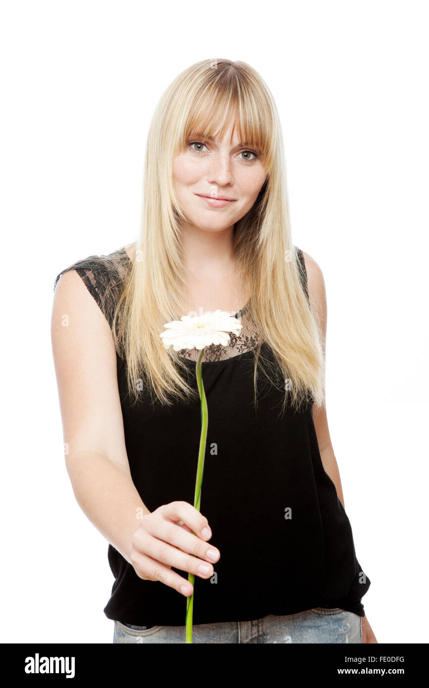 young beautiful blond haired girl gives you a flower in front of white
