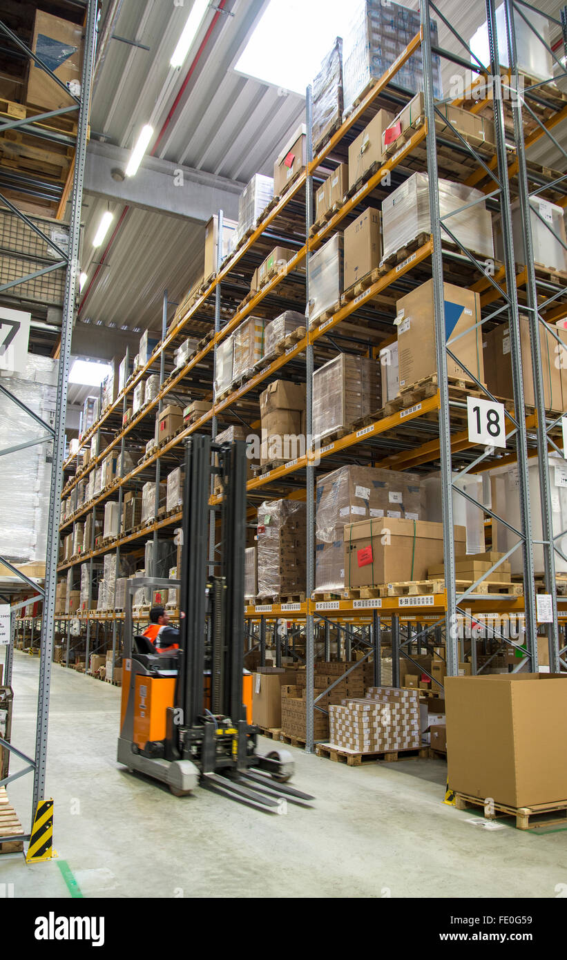 A forklift in front of a high shelf in a warehouse. Stock Photo