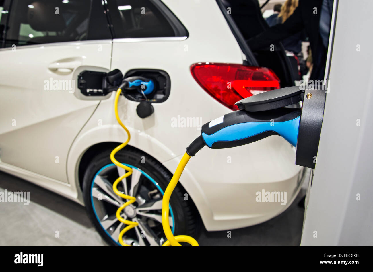 An electric car is connected to a charging station and is being charged. Stock Photo