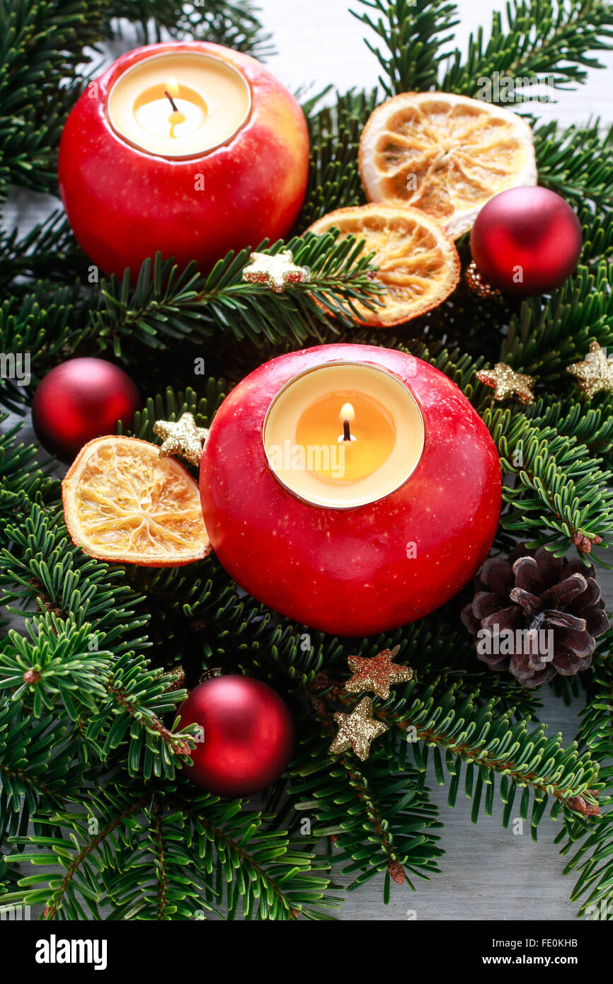 Red apple with candle inside standing on fir branch. Dried fruits and