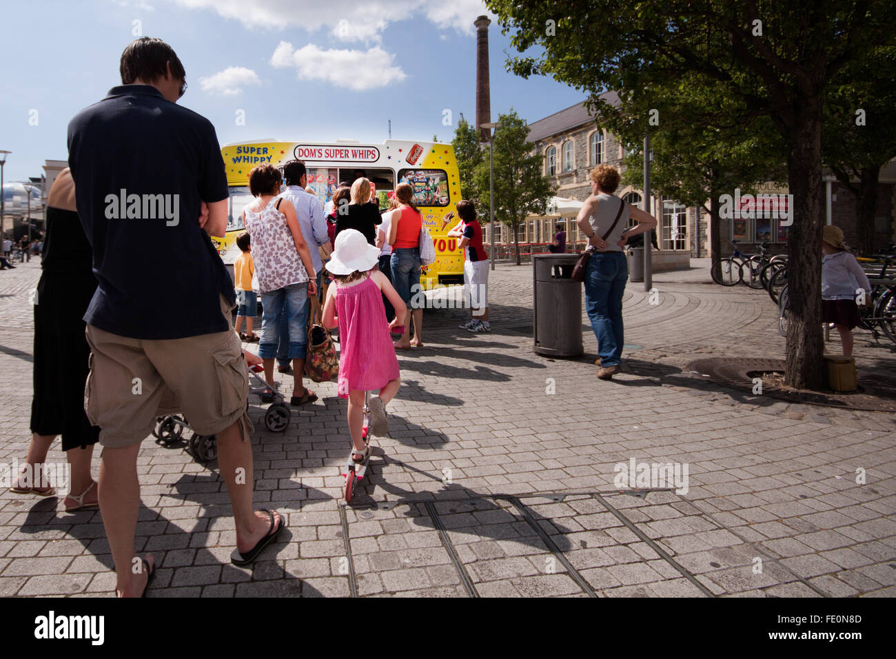 A queue of people waiting to by ice cream from a parked ice cream van on a warm summer day Stock Photo