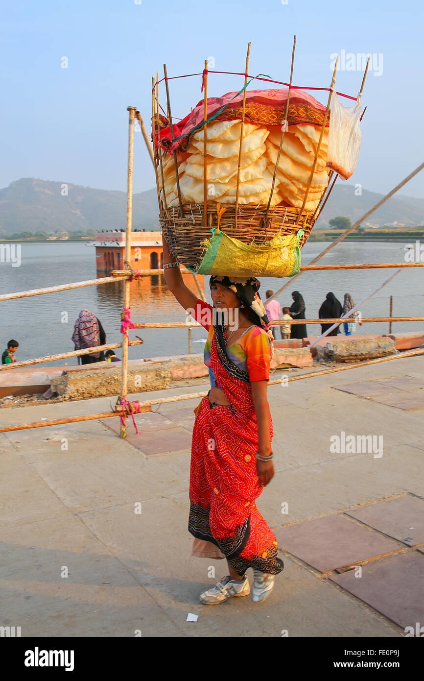 Indian woman with basket on her head walking by Man Sagar Lake in Jaipur, Rajasthan, India. Stock Photo