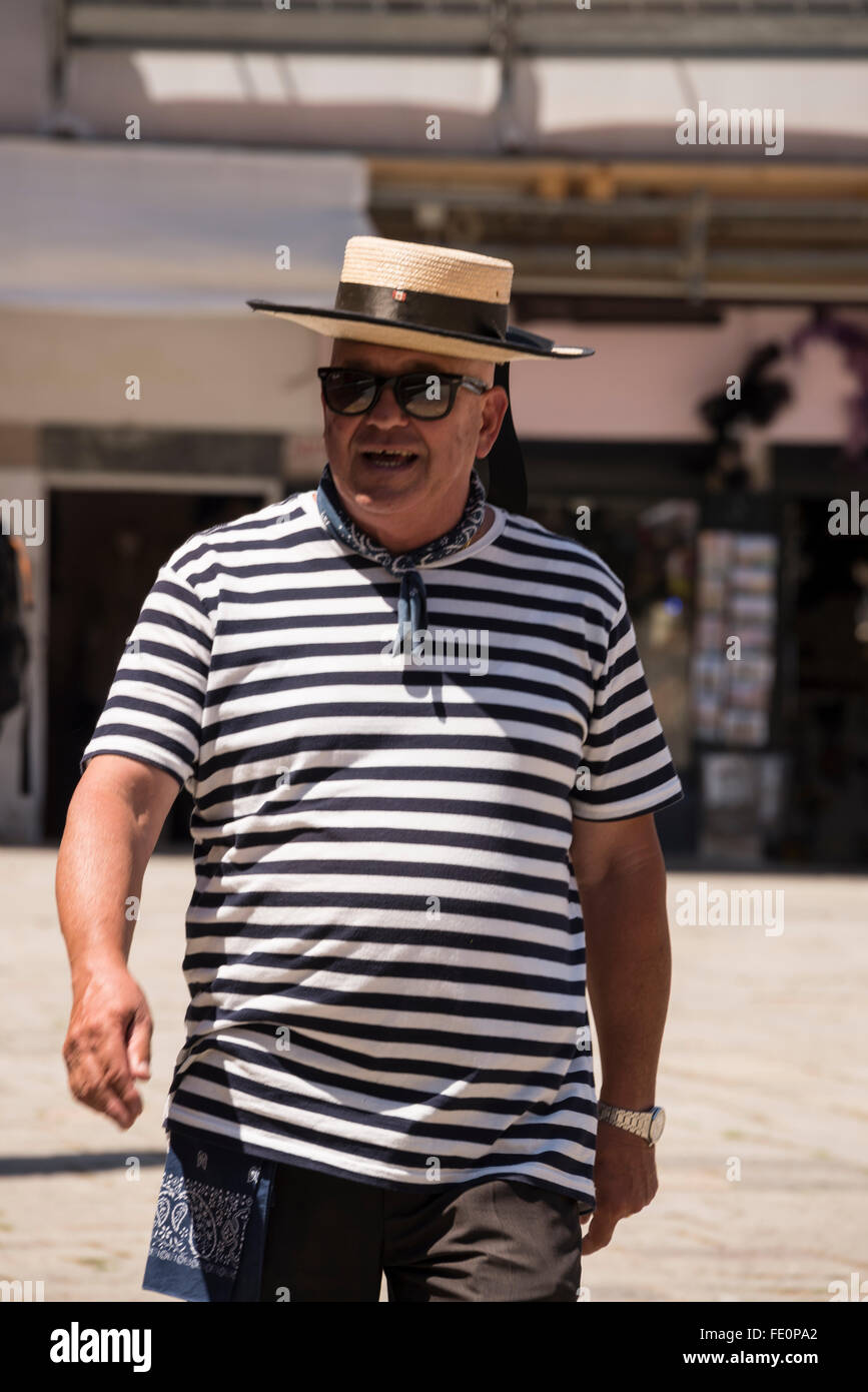 A gondolier wearing his blue & white striped shirt and boater with a blue band in Venice, Italy Stock Photo