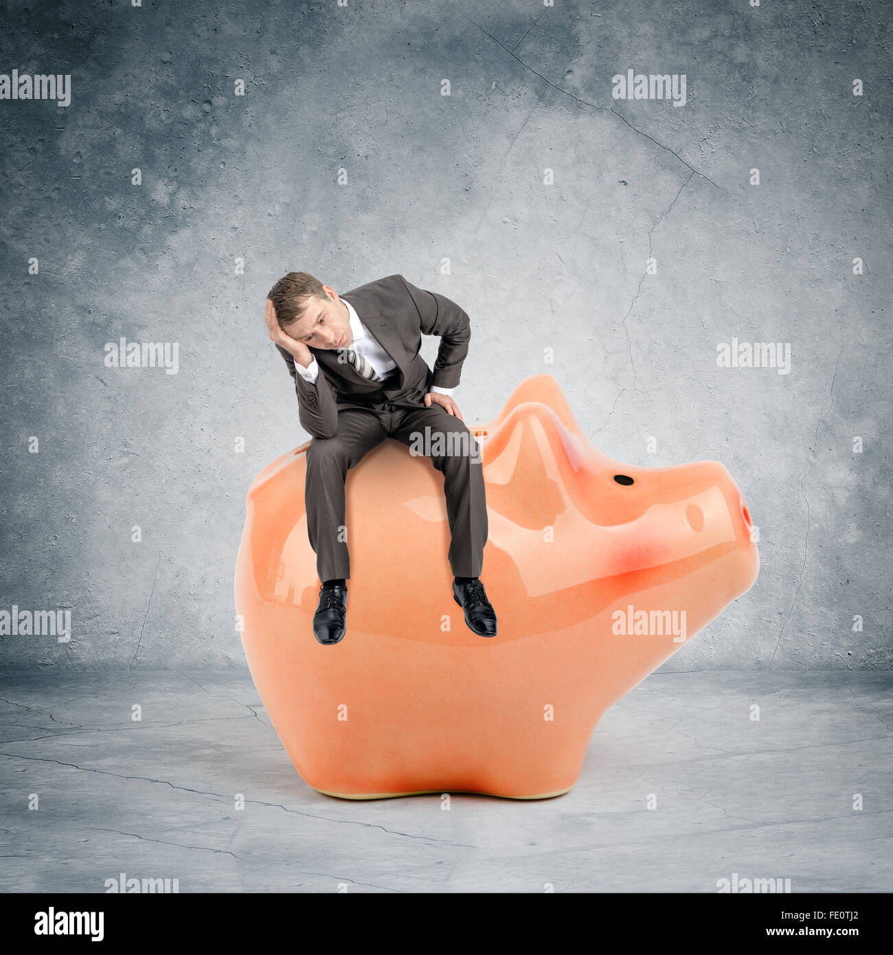 Sad businessman sitting on big piggy bank Stock Photo - Alamy